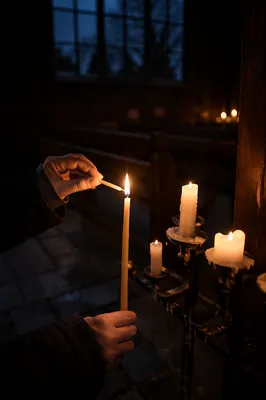 Hands Lighting Candle in Dark Chapel