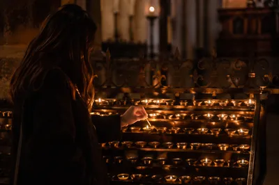 Person Lighting Votive Candle in Dark Chapel