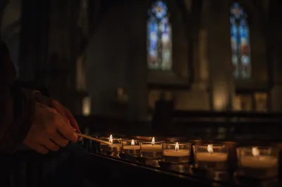 Lighting Votive Candle in Dark Church