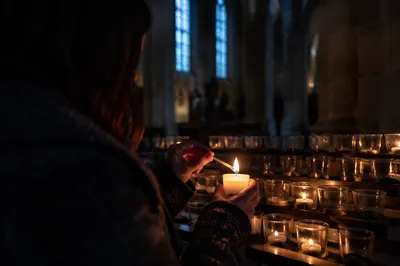 Person Lighting Candle in Quiet Church
