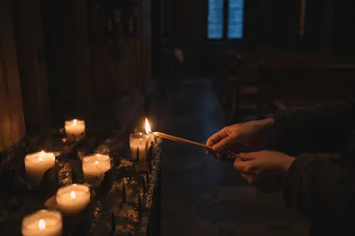 Hands Lighting Candle in Dark Chapel