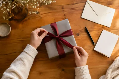 Hands Opening Burgundy Ribbon Gift Box
