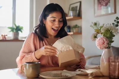 Young Woman Opening Gift Box Indoors