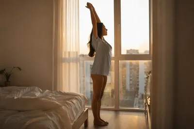 Woman Stretching by Window at Dawn