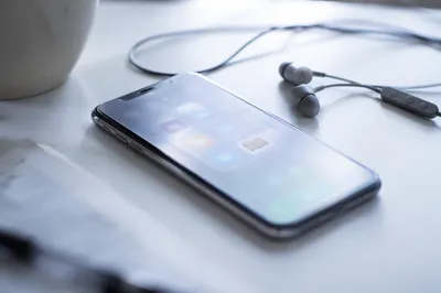 Smartphone and Earbuds on White Desk