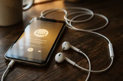 Smartphone and Earbuds on Wooden Table