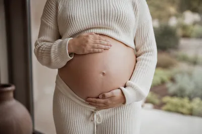 Pregnant Woman Cradling Belly in Natural Light