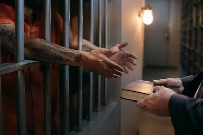 Hands Reaching Through Prison Cell Bars