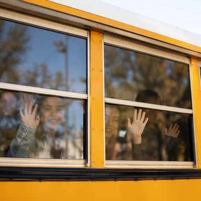 Children Waving From School Bus Window
