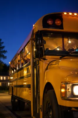 Children Waving From School Bus at Dusk