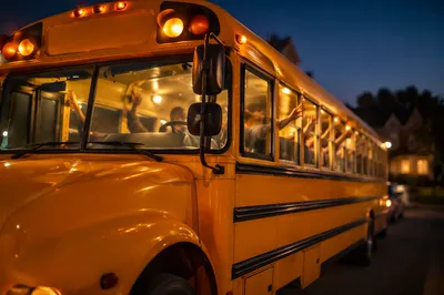 Children Waving From School Bus at Dusk