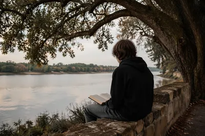 Teen Reading Bible Under Lakeside Tree