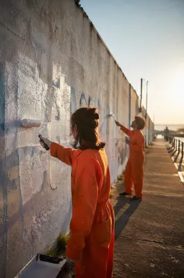 Community Volunteers Repainting Wall at Sunset