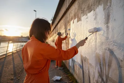 Community Volunteers Repainting Wall at Sunset