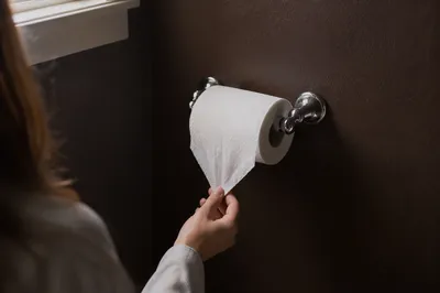 Woman Reaching for Tissue in Quiet Bathroom