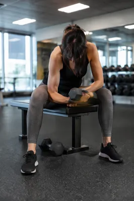 Focused Woman Training With Dumbbell in Gym