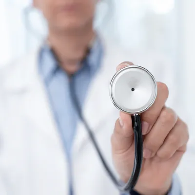 Clinician Holding Stethoscope in Exam Room