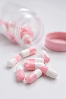 Pink and White Capsules on Glossy Surface