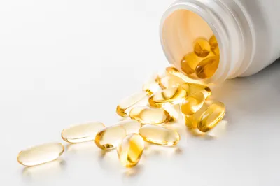 Golden Softgel Capsules Spilling From Pharmacy Bottle
