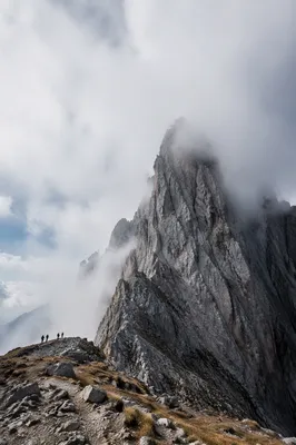 Misty Alpine Hikers Beneath Jagged Mountain Peak