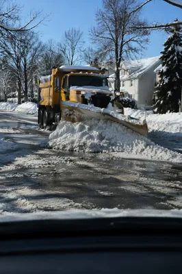 Yellow Snowplow Clearing Blizzard-Covered Suburban Road