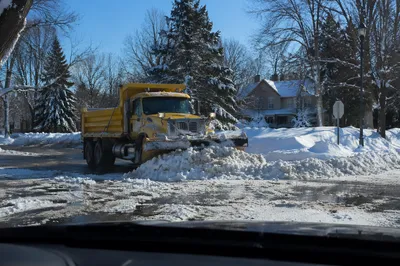 Yellow Snowplow Clearing Blizzard Covered Suburban Road
