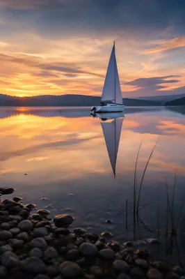 Solitary Sailboat on Calm Sunset Lake
