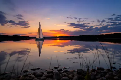 Solitary Sailboat on Calm Sunset Lake