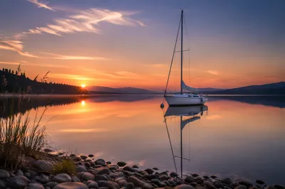 Lone Sailboat on Calm Lake Sunset