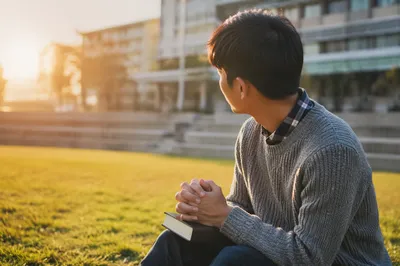 Asian University Student Praying on Campus Lawn