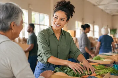 Young Volunteer Arranging Vegetables at Food Pantry