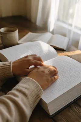 Hands Reading Braille Bible in Soft Light