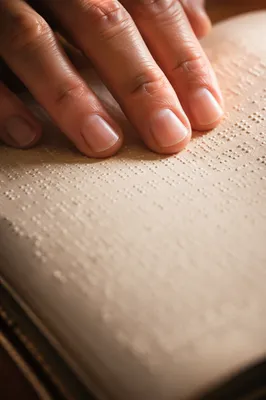 Hands Reading Braille Bible in Warm Light