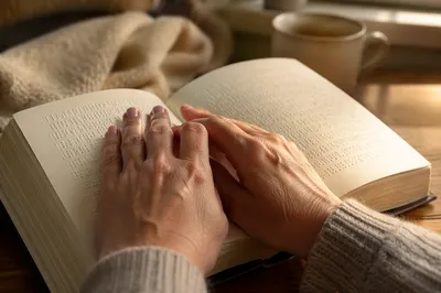 Hands Reading Braille Bible in Morning Light