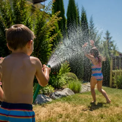 Children Playing in Summer Sprinkler Yard