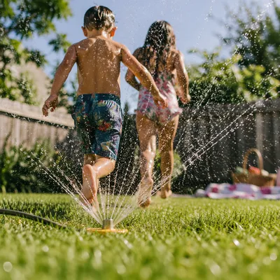 Children Running Through Summer Sprinkler