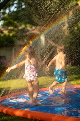 Children Playing in Summer Sprinkler Rainbow