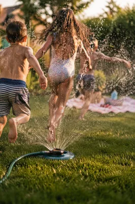 Children Running Through Summer Sprinkler