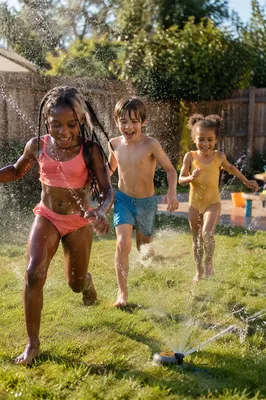 Children Running Through Backyard Sprinkler