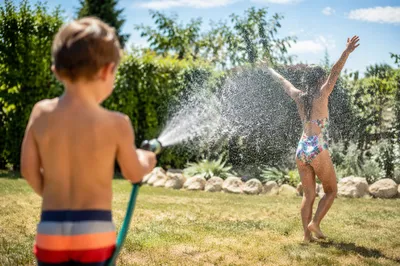 Children Playing in Summer Sprinkler Backyard