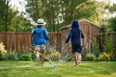 Children Running Through Backyard Sprinkler
