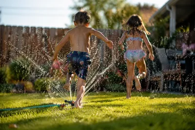 Children Running Through Summer Sprinkler