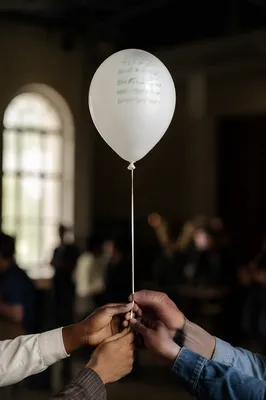White Balloon Held by Diverse Hands
