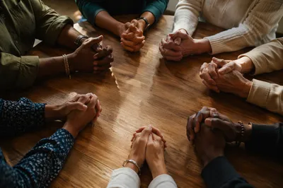 Diverse Prayer Circle Around Wooden Table