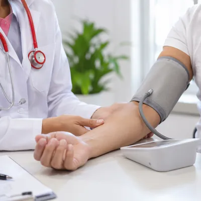 Doctor Taking Blood Pressure in Clinic