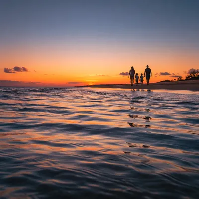 Family Silhouettes Walking Along Sunset Beach