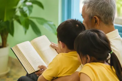 Grandfather Reading Bible Story to Grandchildren