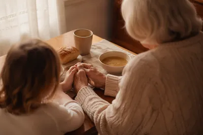 Grandmother Teaching Grandchild to Pray at Table