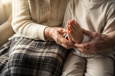 Grandmother Guiding Child Hands in Prayer