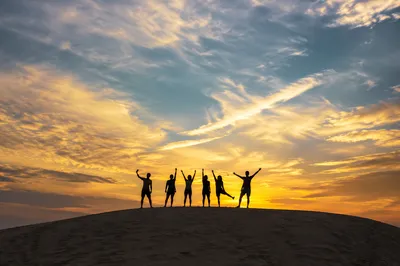 Friends Celebrating Sunset on Sandy Dune